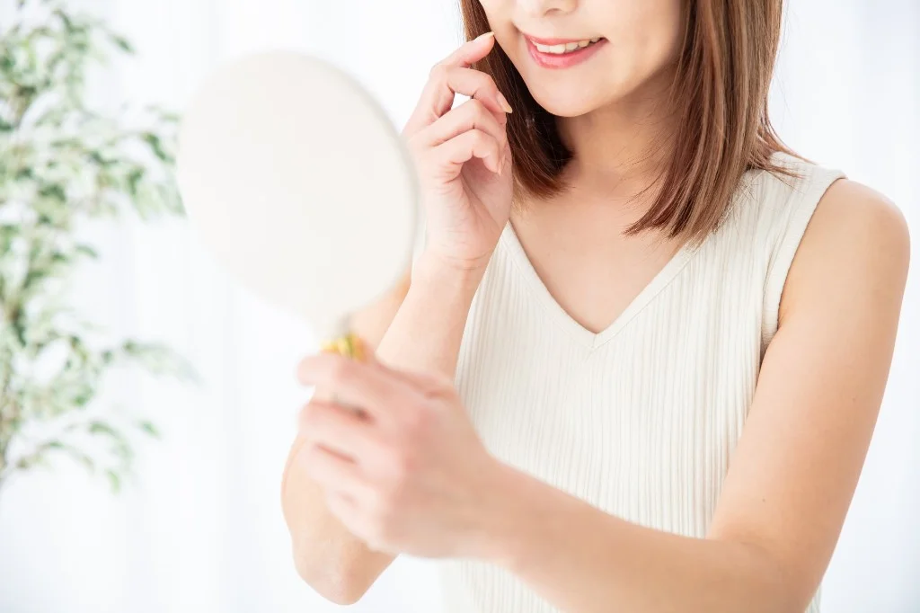 鏡で笑顔の歯を確認する女性