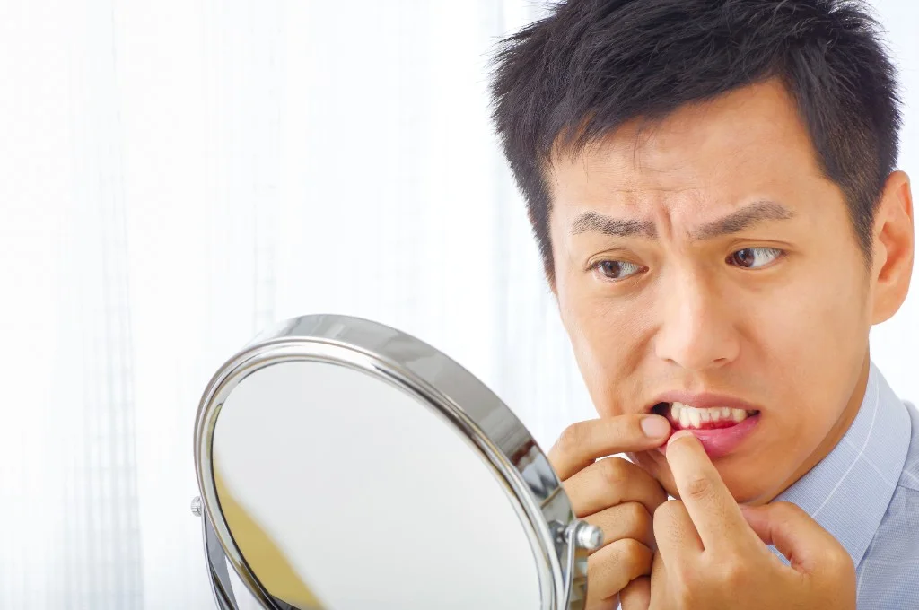 鏡で歯茎の状態を確認している男性