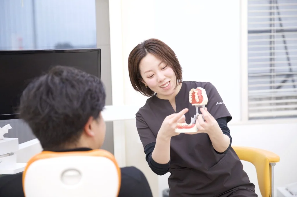 歯科模型を用いて患者へ説明する歯科衛生士