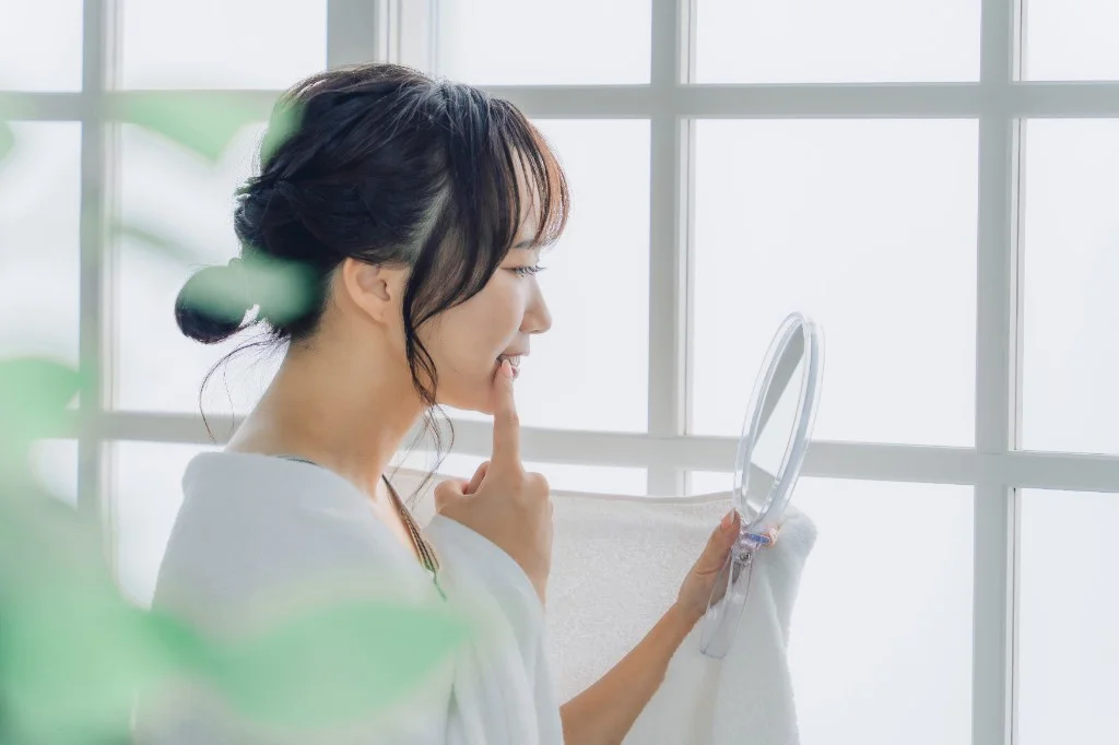 鏡で歯の色を確認する女性